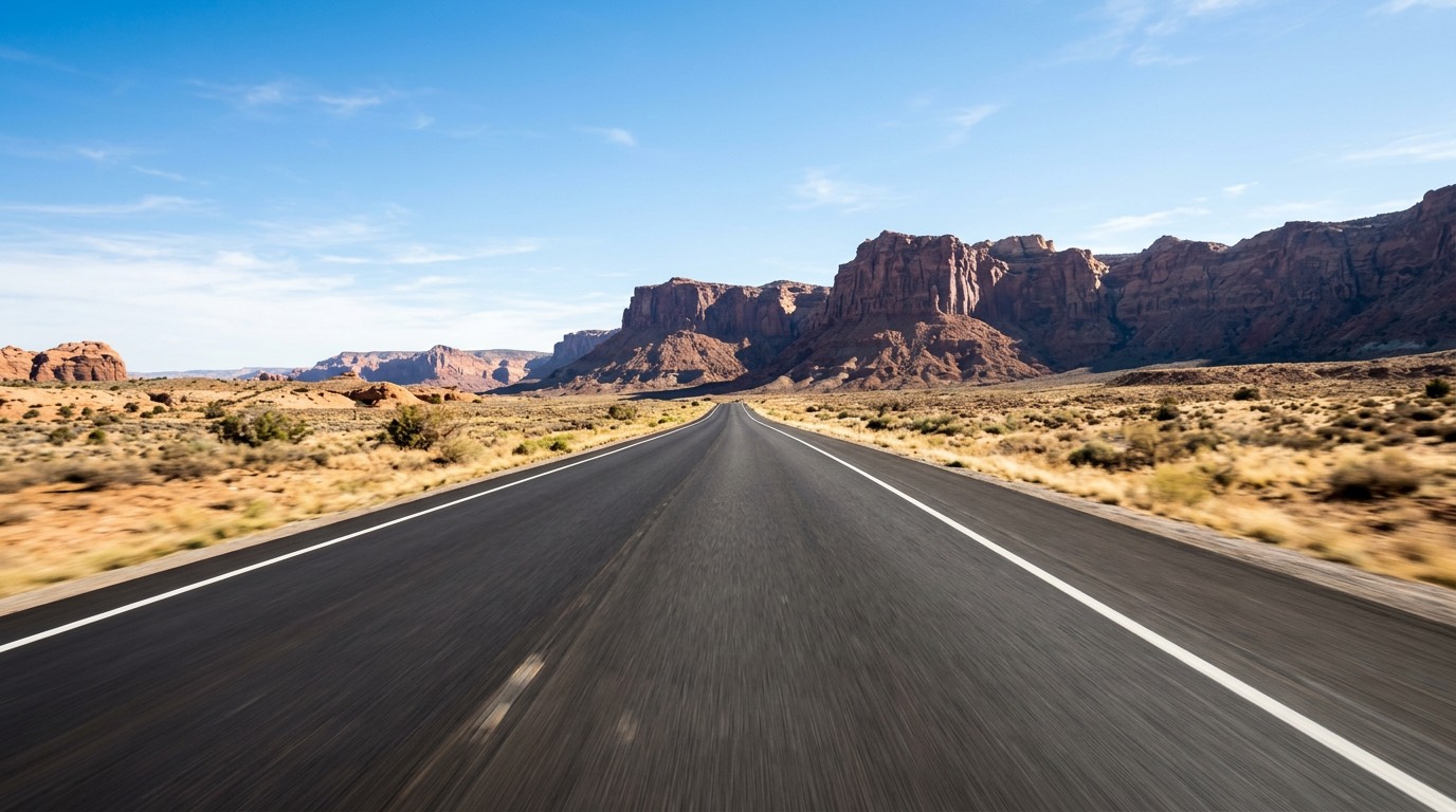 POV opening: empty desert highway toward red-rock cliffs